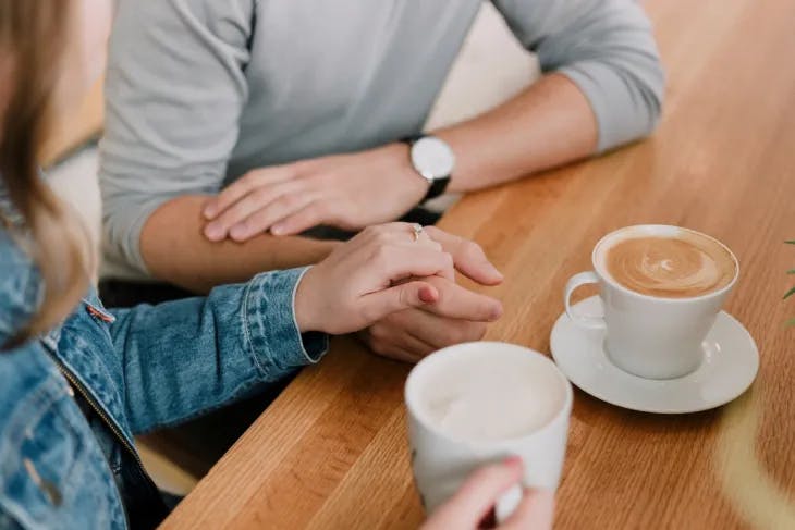 Couple enjoying coffee together while holding hands