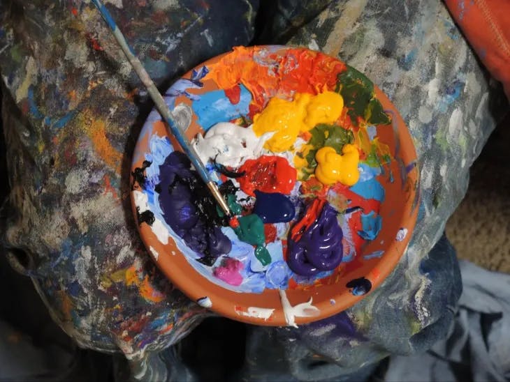 a person holding a bowl of paint and a brush