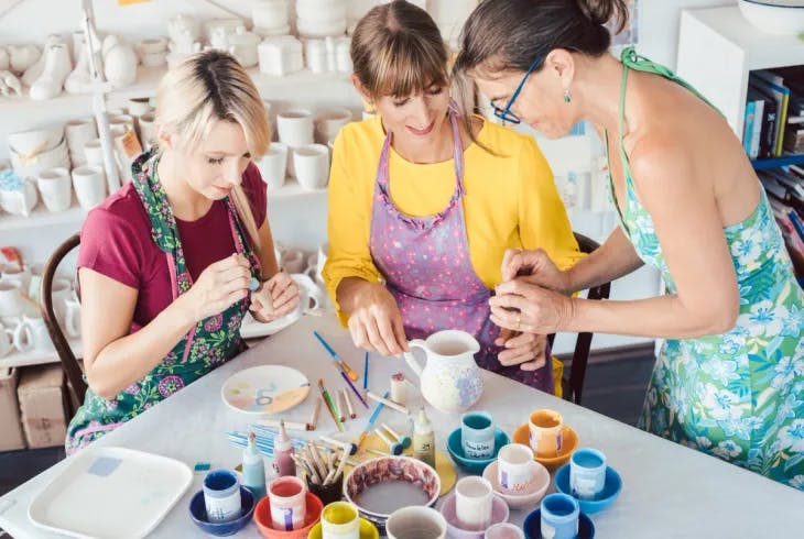 Three women painting cups