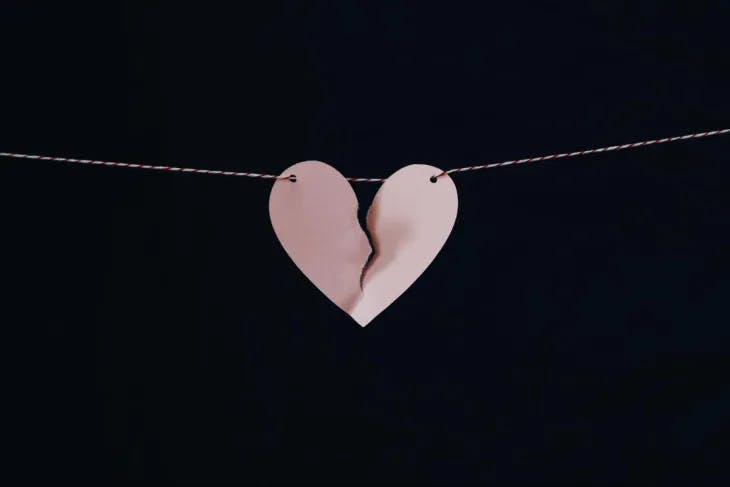 Torn pink paper heart on a string