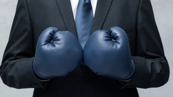 Man wearing a suit and blue boxing gloves