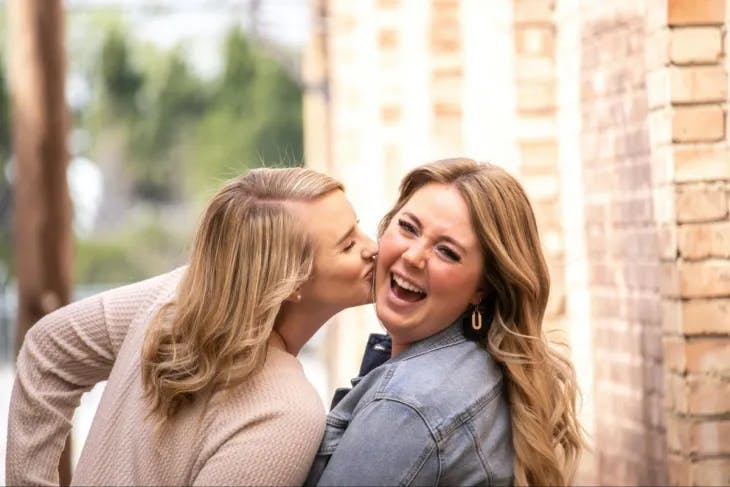 A woman kissing her friend on the cheek - enneagram 6 and 8 misidentification