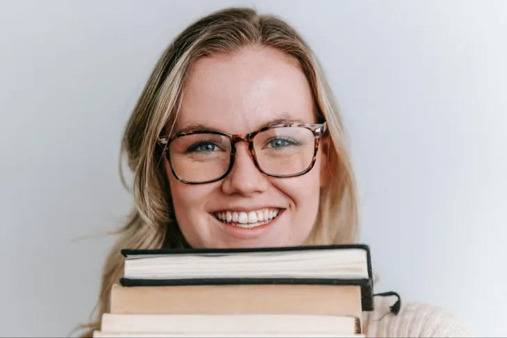 A woman holding a stack of books