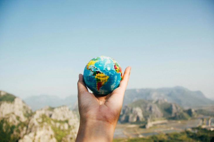Person holding a globe against a scenic backdrop