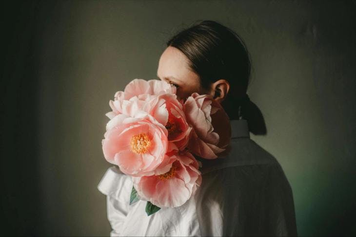 A woman holding flowers in front of her face