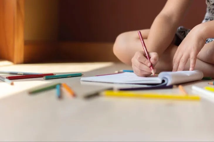 Kid using markers to color in a notebook