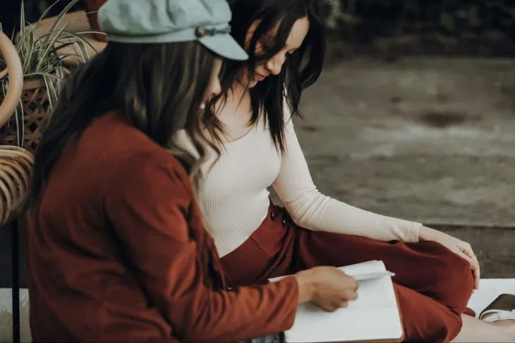 Two girls looking at a notebook