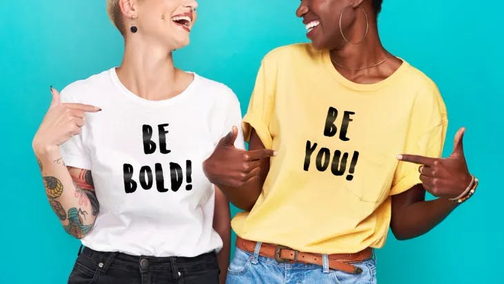 Two women wearing a shirt that says 'Be Bold'