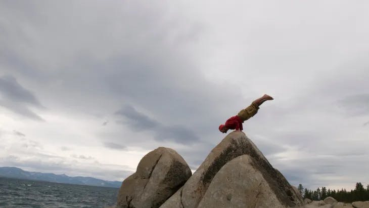 Man balancing in a handstand on a rock