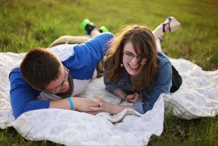 A couple laughing and laying on grass
