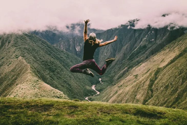 Woman jumping atop a hill