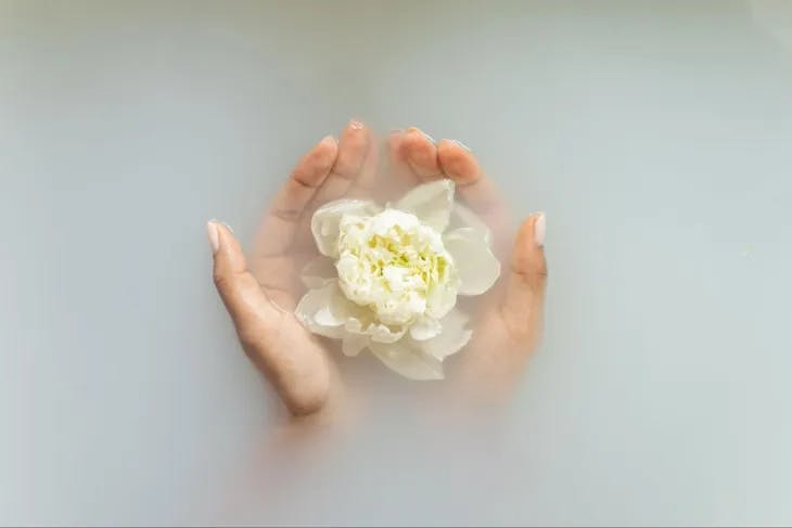 Hands delicately holding a flower submerged in water