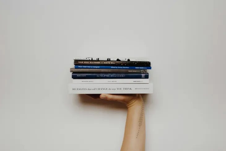 A hand holding a stack of books