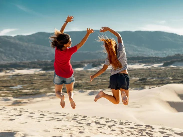 Two girls jumping on a beach