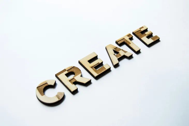 The word 'create' crafted from wood