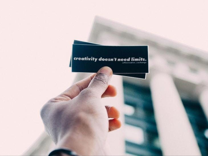 Man holding a card that says 'Creativity Doesn't Need Limits'