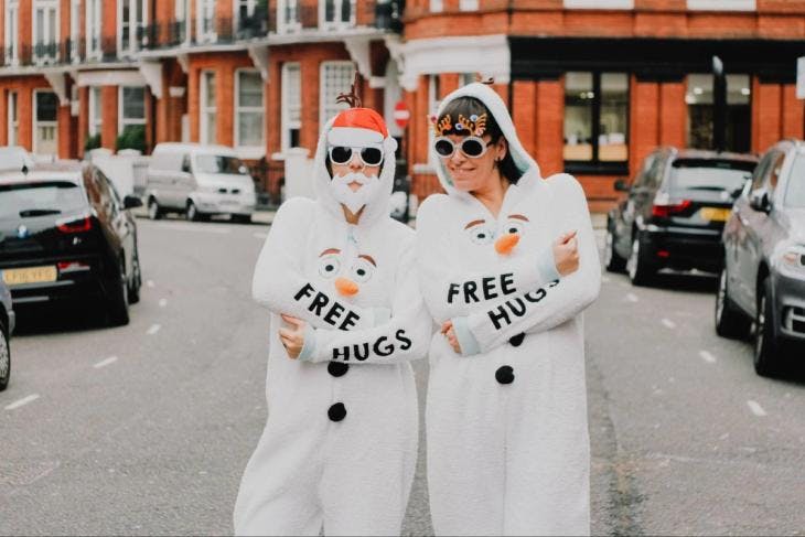Two women wearing a snowman suit with a 'Free Hugs' sign