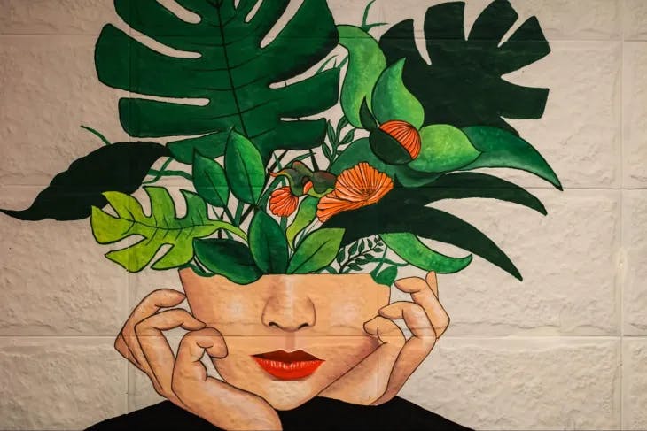A painting of a girl's face with plants growing from her head