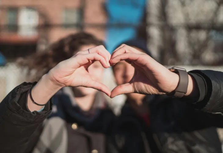 Two people forming a heart shape with their hands