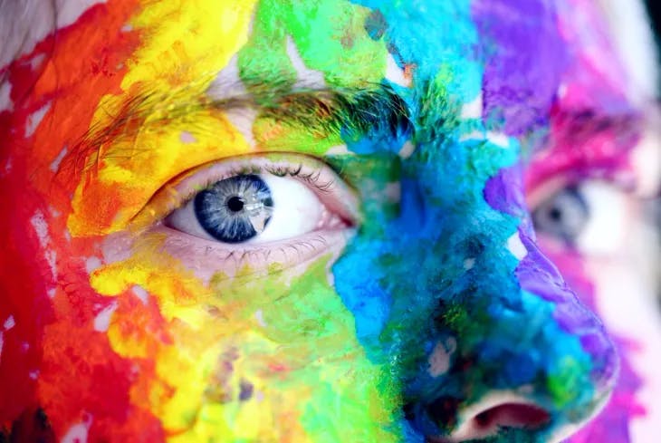 Face fully painted in vibrant rainbow colors