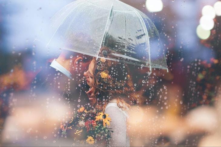 Couple standing in rain under umbrella