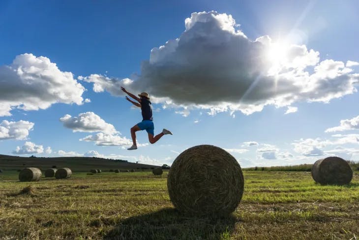 Woman jumping from a hay bale